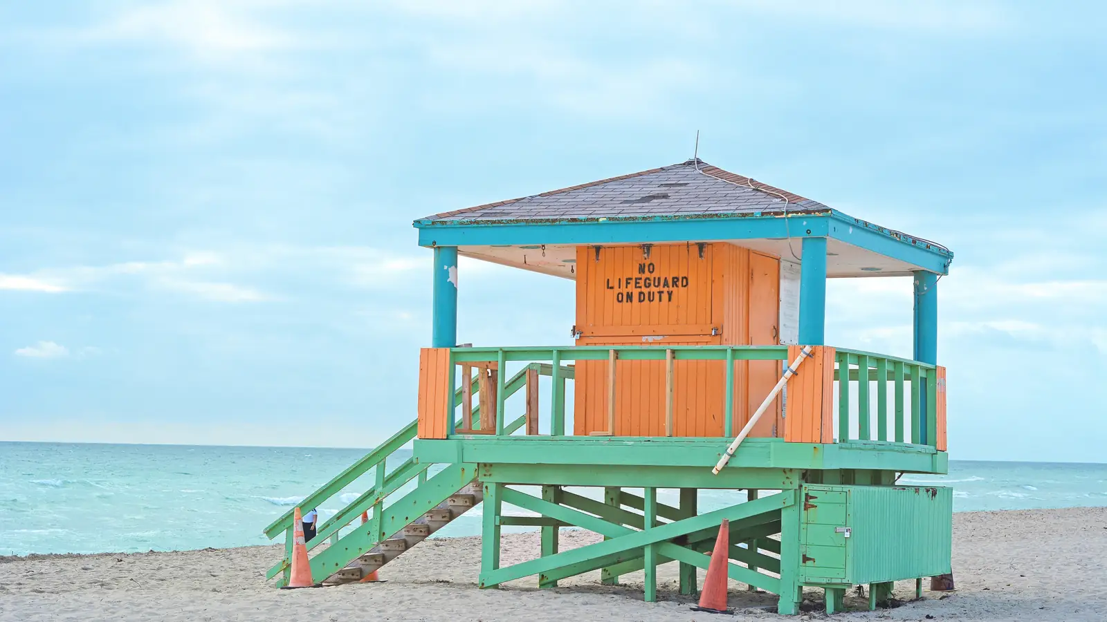 A teal and orange lifeguard tower on the sand at South Beach, Miami